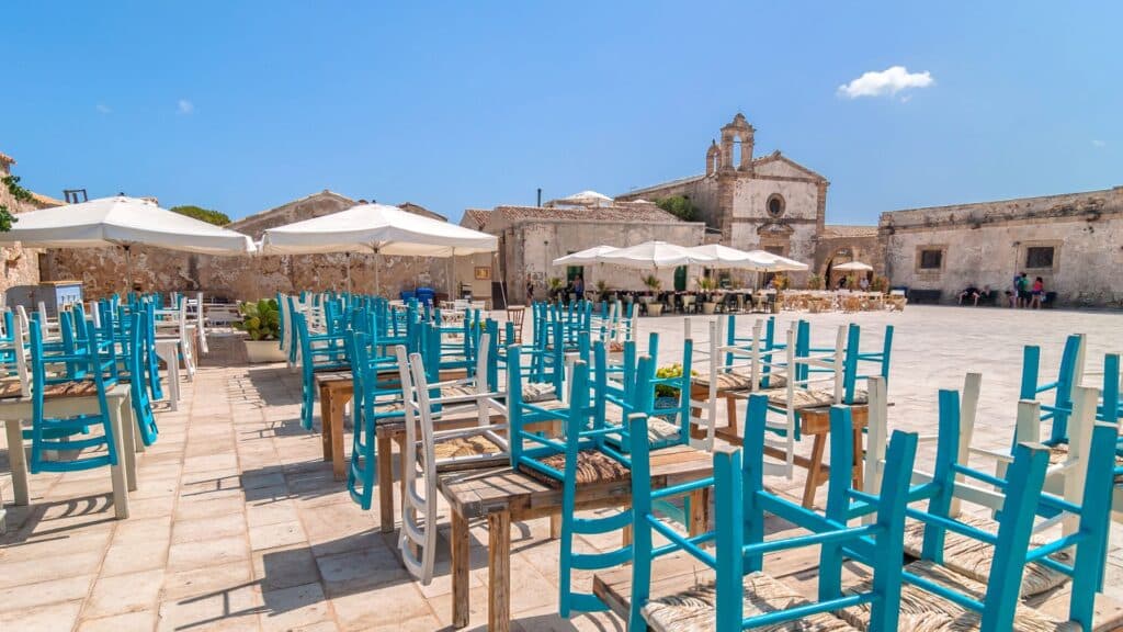 Chairs and tables in the quiet square of Marzamemi, a peaceful Sicilian fishing village