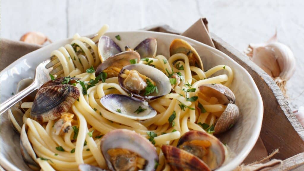 Spaghetti alle Vongole, a traditional Italian dish, showcasing the flavors of Naples and the Amalfi Coast - Travel to Amalfi Coast, Travel to Napoli, Italian Cuisine.