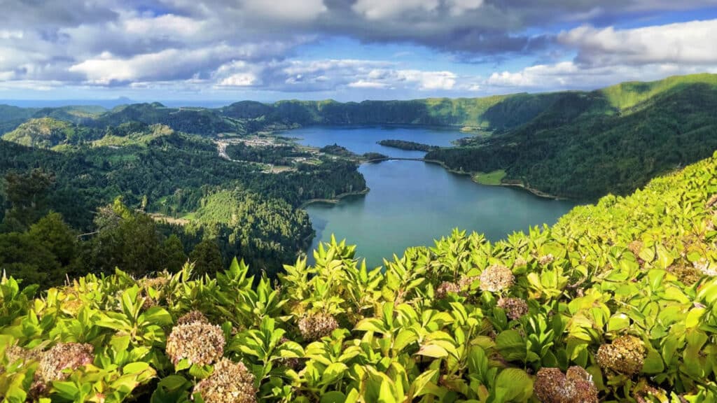 A stunning aerial photograph of the Azores' volcanic craters surrounded by lush greenery, showcasing an adventure travel paradise.