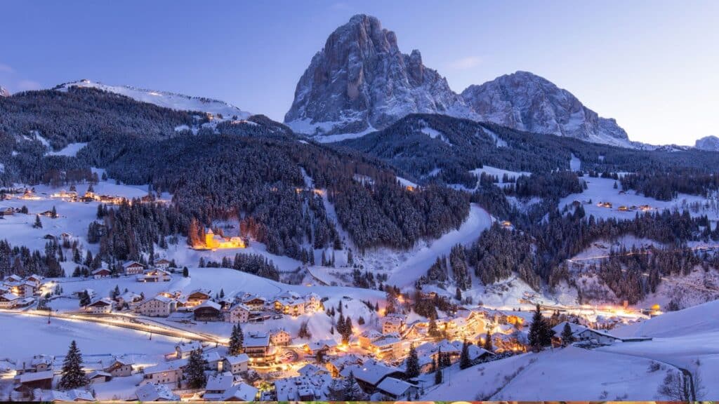 Christmas Markets in the Dolomites - A charming mountain town in the Dolomites covered in snow, illuminated at night, representing the festive spirit of Christmas markets in Alpine Italy.