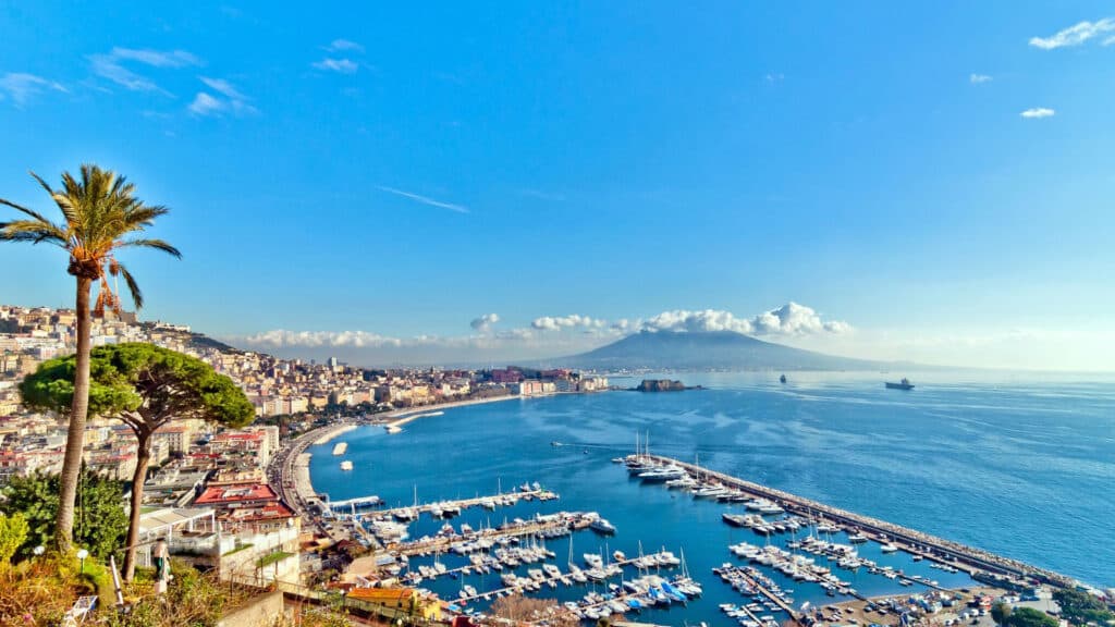 Panoramic view of Naples with Mount Vesuvius in the background, showcasing the city’s coastal beauty and historic charm.