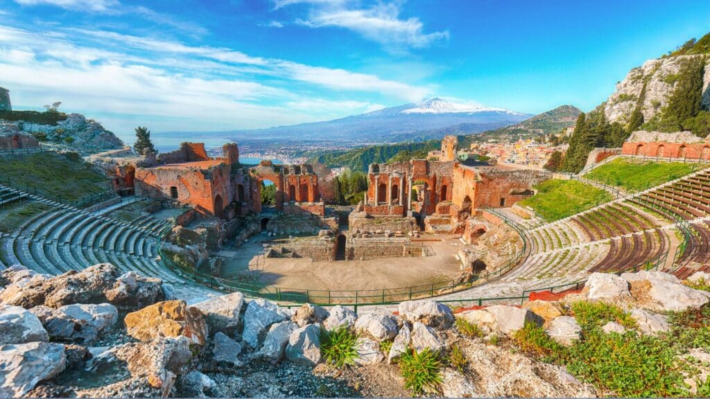 The Ancient Greek Theater In Taormina With A Stunning View Of Mount Etna In The Background.